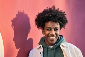Smiling man in a hoodie and coat with an afro